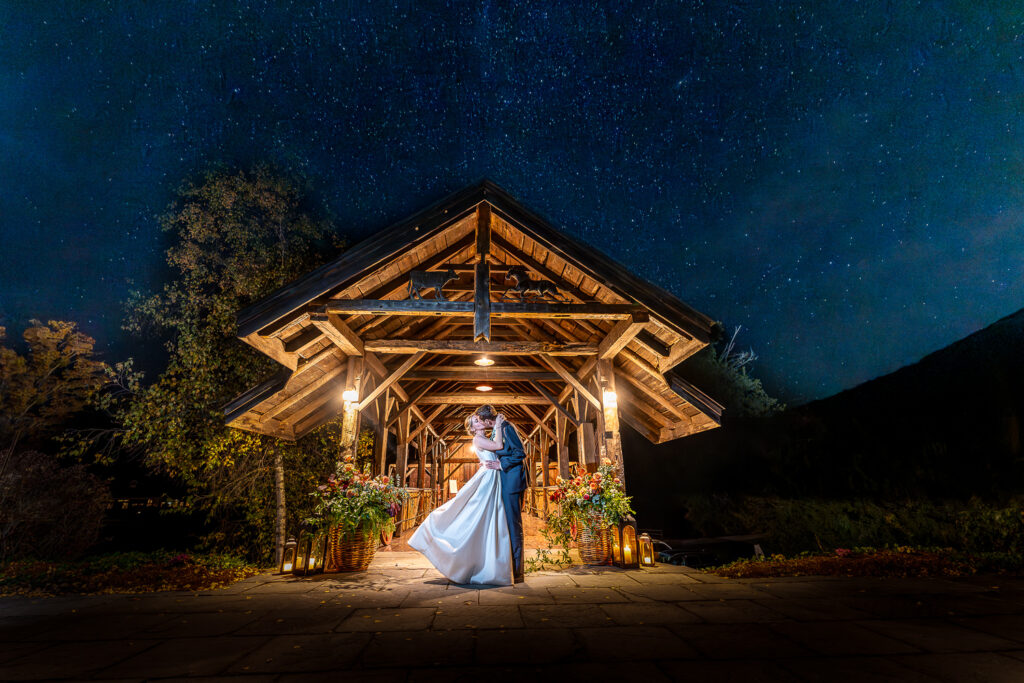 bride and groom kissing in front of barn with stars above them.